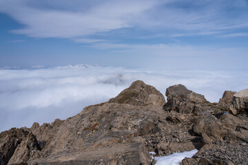 Dramatic high mountain landscape with snow, rocks and low clouds