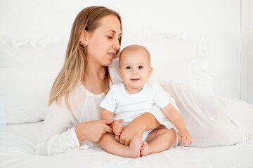 mother and baby hugging and kissing on the bed at home, maternal love and care, mother and child