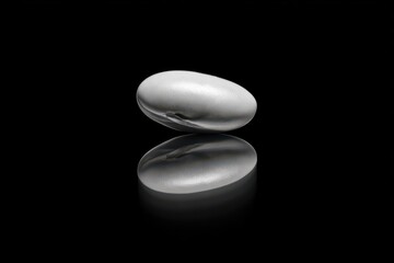 Monochrome Minimalism - A Single Pill on Reflective Black Surface.