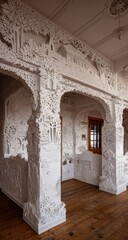 Intricate white relief carvings depicting a miniature landscape, showcased within a room's architectural framework.