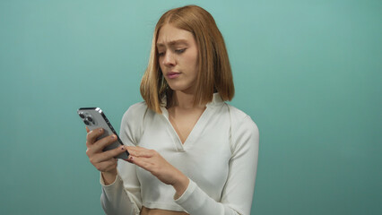 Woman puzzled with smartphone over isolated blue background wall, expressing confusion with blonde...