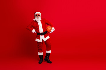 Festive Santa Claus Holding a Basketball Posing Against Bright Red Background - Christmas and Holiday Spirit