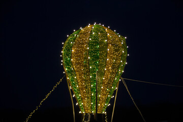 Illuminated hot air balloon decoration shines brightly against the night sky at a festive event