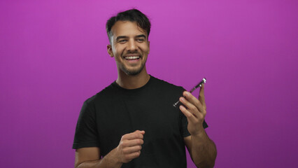 Young man dancing with a smartphone against a vibrant pink background, exuding joy and energy while...