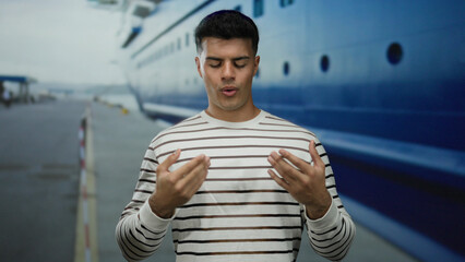 Man standing focused on breathing exercise by cruise liner at port, wearing striped shirt, closed eyes suggest relaxation, vivid depiction of mindfulness outdoors.