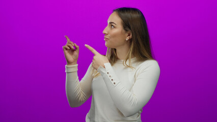 Naklejka premium Woman pointing enthusiastically against vivid pink background, showcasing excitement, expression, and positivity in an isolated setting