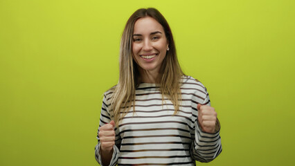 Obraz premium Woman smiling joyfully in front of an isolated yellow backdrop, wearing a striped shirt, showcasing happiness and youthful energy in a studio setting.