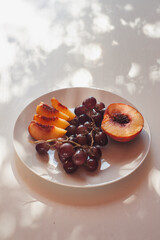 Peach and Grapes on White Plate with Floral Shadows, Sardinia, Vertical Close Up with Copy Space