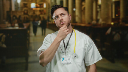 Obraz premium Young man with beard and stethoscope inside a church, conveying the juxtaposition of medical profession and spiritual environment.