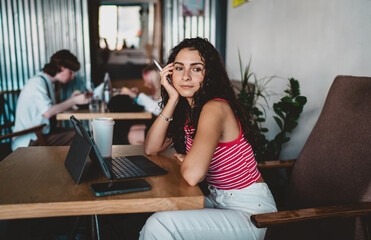 Creative young woman pauses with stylus resting on face, expressing thoughtful reflection and...