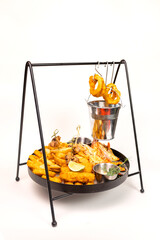 Crispy shrimp, calamari rings, and potatoes in a metal basket on White background