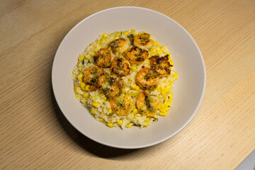 A plate of corn risotto with prawn.