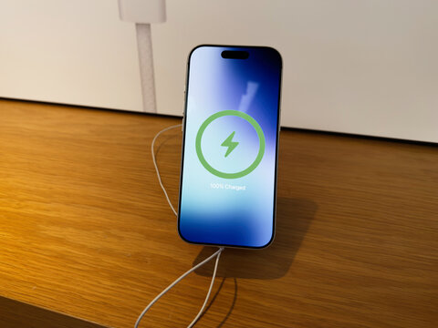 Smartphone iPhone 17 Pro on wooden desk charging wirelessly with green indicator showing full battery
