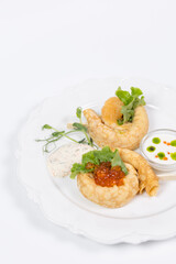  Top view Elegant crepes with red caviar and greens on white plate.