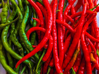 Fresh red and green chili peppers arranged together on a flat surface