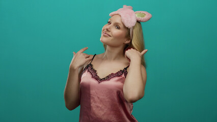 Woman in pink nightwear and sleep mask poses confidently against a vibrant blue background.