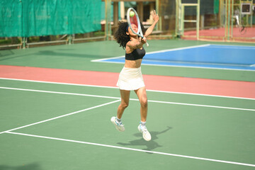 Obraz premium Energetic African sportswoman jumping to receive a tennis serve, practicing agility and precision on the court