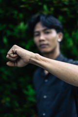 Young man showing fist in nature setting