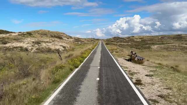 4K video of a riding bike on a bicycle path moving outdoor at daytime during autumn season surrounded with dunes near the coast in Holland in Zandvoort in The Netherlands.