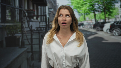 Fototapeta premium Woman on city street in frontal pose with pouting face and rolling eyes, white blouse and visible belt; annoyance.
