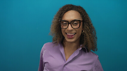 Woman flips middle finger at camera while wearing glasses and a purple shirt in a blue studio;...