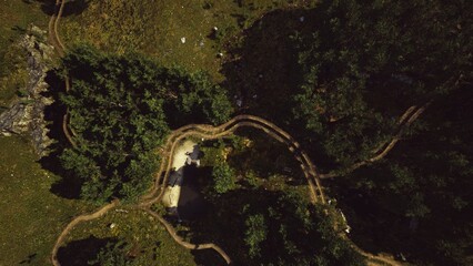 A birds eye view reveals winding trails through vibrant green forests, leading to a tranquil clearing. The natural beauty suggests peaceful exploration and adventure in the mountains.