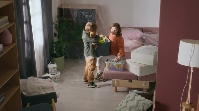 High angle shot of happy family carrying boxes and talking to each other, going through relocation to new apartment