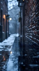 A highly reflective black counter or table edge in a snowy, dark city alley with a brick wall and unfocused background lights. Cold, moody urban scene