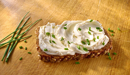 Vollkornbrot mit Quark und Schnittlauch auf hellem Holzfond, Schwarzbrot, Frischkäse, 
