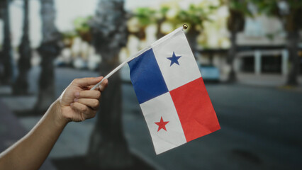 Caucasian man holding panamanian flag on a city street, symbolizing national pride and celebration...