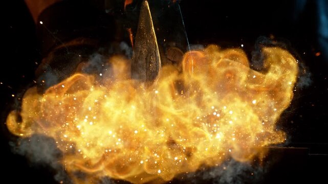 Close-up of blacksmith forging glowing hot iron on anvil with flying sparks. Super slow motion filmed on high-speed cinema camera at 1000 fps