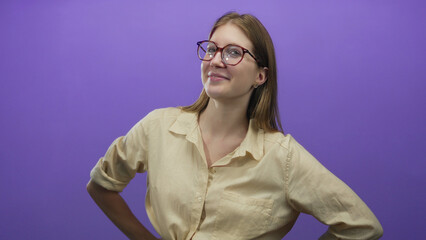 Blonde woman wearing glasses sticks out tongue, raises hands and smiles while tilting head in...