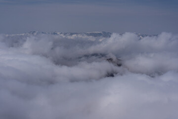 Obraz premium Misty mountain peak covered in snow, floating above dense clouds