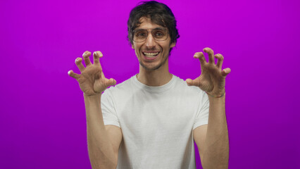 Man wearing glasses and white shirt showing claw gesture with hands in studio; playfulness and...