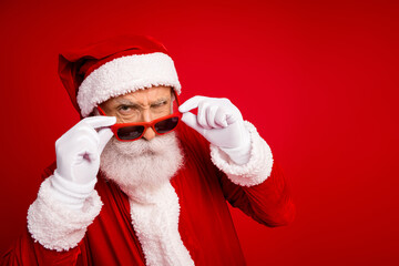 Santa Claus in a festive pose wearing stylish sunglas s against a red background expressing holiday...