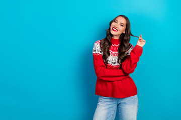 Stylish woman wearing a red holiday sweater smiling joyfully against a blue background during festive winter season