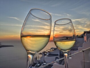 Two glasses of white wine at sunset overlooking caldera of Santorini, Cyclades Islands, Greece