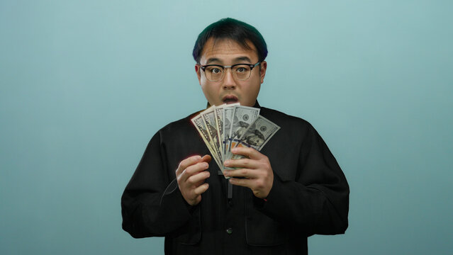 Priest holding us dollars surprised against blue background, showcasing currency with a contemplative expression - Powered by Adobe