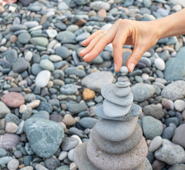 Woman making cairn on the beach. Activity