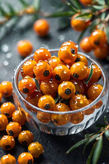 Juicy sea buckthorn berries, collected in a transparent glass bowl, with sparkling dew drops on the surface