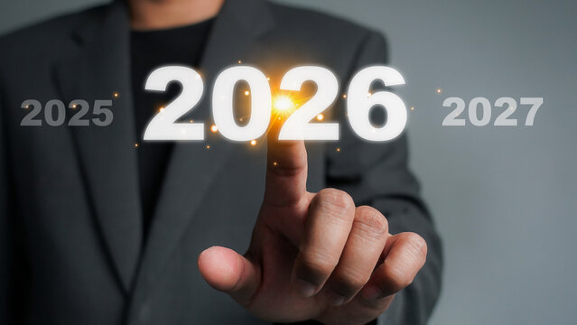 Businessman hand drawing line for increasing arrow from 2025 to 2026 for preparation new year