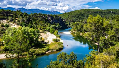 Panoramic view of a river winding through lush green valleys under a partly cloudy sky