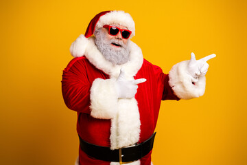 Santa Claus in vibrant sunglass showing finger guns with cheerful expression against a bold yellow backdrop