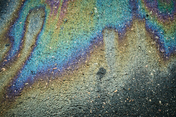 Asphalt road showing colorful oil slick creating an abstract iridescent texture.