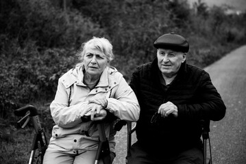Fototapeta premium Elderly couple taking a break sitting on walker after walk in walk smiling happy together