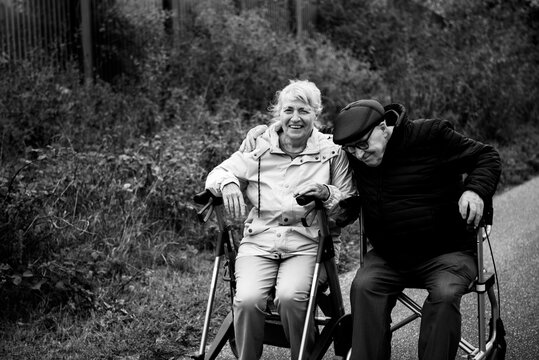 Elderly couple taking a break sitting on walker after walk in walk smiling happy together