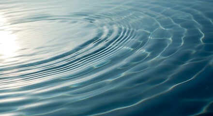 Fototapeta premium Gentle ripples spreading across calm blue water surface with sunlight reflection.