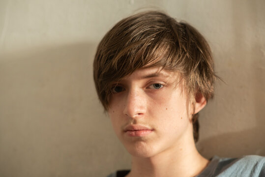 Portrait of a 13 year old boy against a white wall.