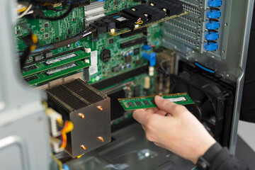 Male IT technician installs RAM module in server during hardware upgrade and maintenance