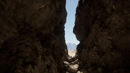 A narrow tunnel between two large rocks, leading into the darkness of a mysterious cave